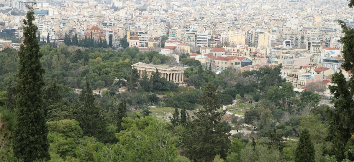 The Temple of Hephaestus surrounded by trees with the city of Athens beyond