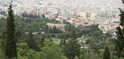 The Temple of Hephaestus surrounded by trees with the city of Athens beyond