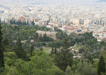 The Temple of Hephaestus surrounded by trees with the city of Athens beyond